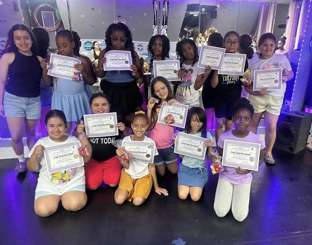 A group of children holding up certificates in front of their faces.